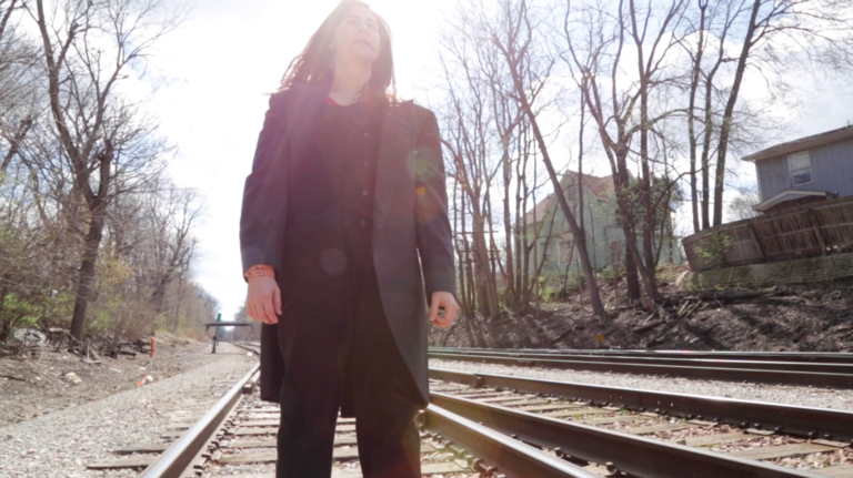 Dancer Kate Vincek standing on abandoned train tracks