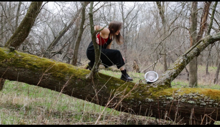 MFA student Kate Vincek performing in a wooded area outdoors