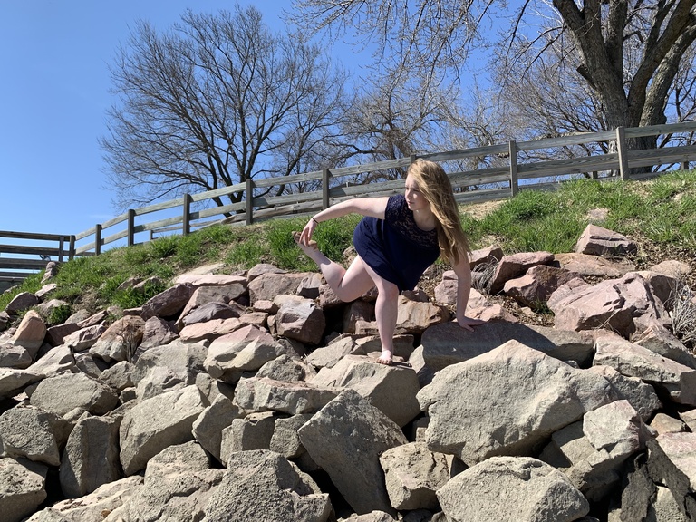 Emily Buttolph dancing outdoors on a large pile of boulders