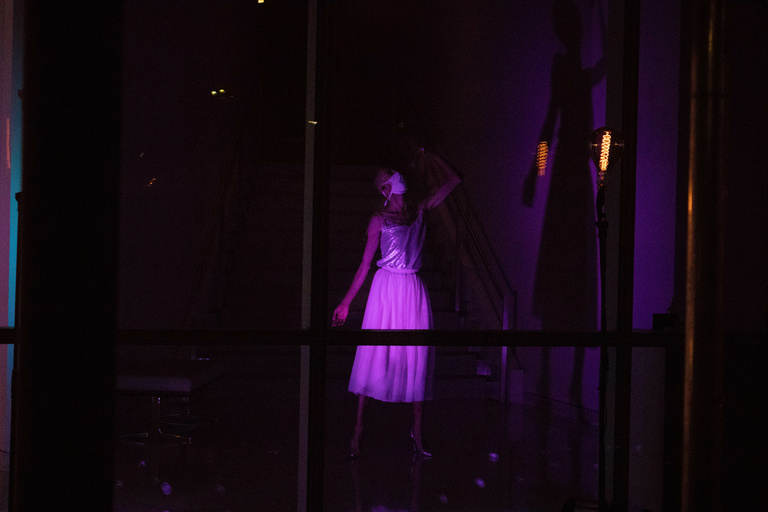 Dancer singing into a microphone, performing behind windows