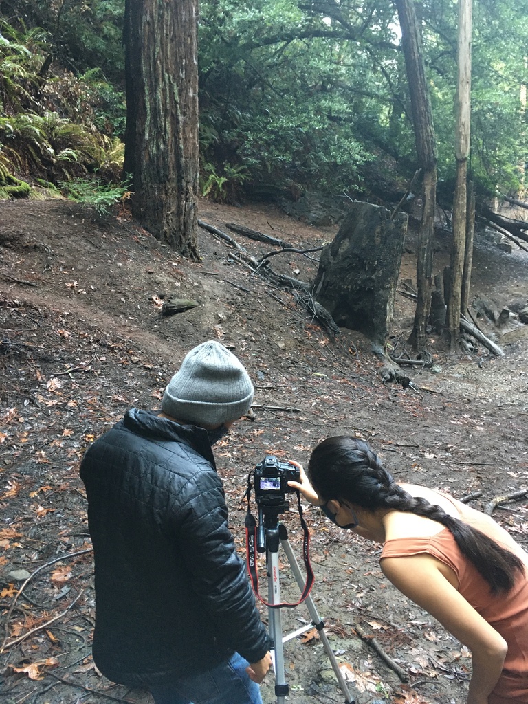 Two people reviewing camera shot in a wooded area