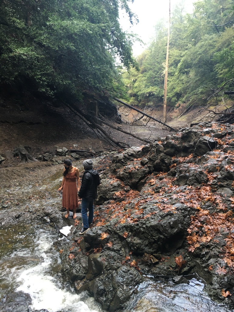 Dancer and videographer standing beside a stream