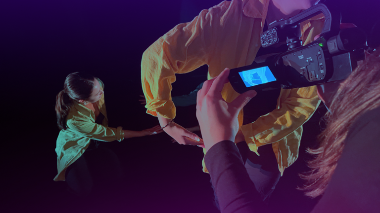 Photo of video camera taking a close up recording of a dancer's hands.
