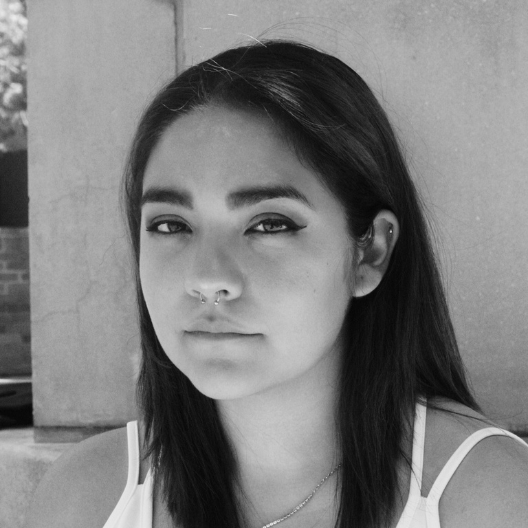 Black and white headshot of Katelyn Perez, with a stone structure in the background