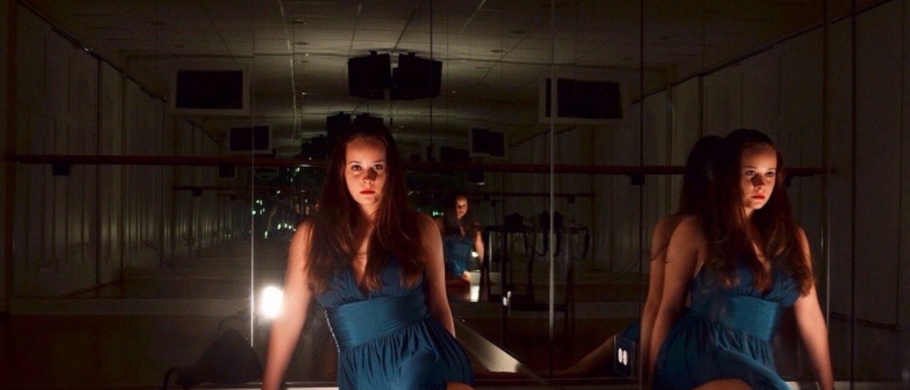 Anna Wetoska seated on a floor, surrounded by mirrors