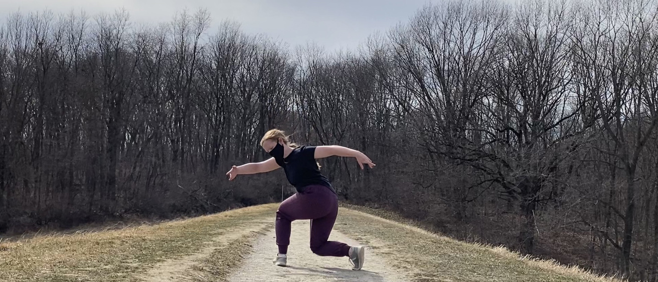 Dancer performing on outdoor trail.