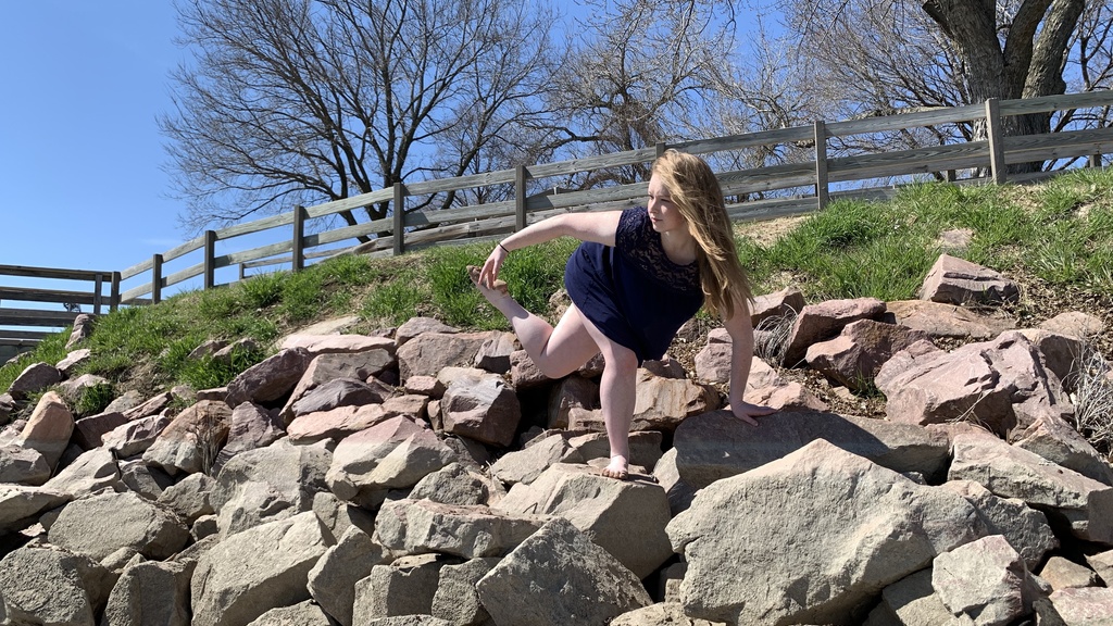 Emily Buttolph dancing outdoors on a large pile of boulders