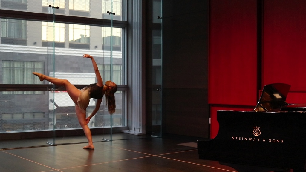 Dancer performing in front of a large window in Voxman recital hall