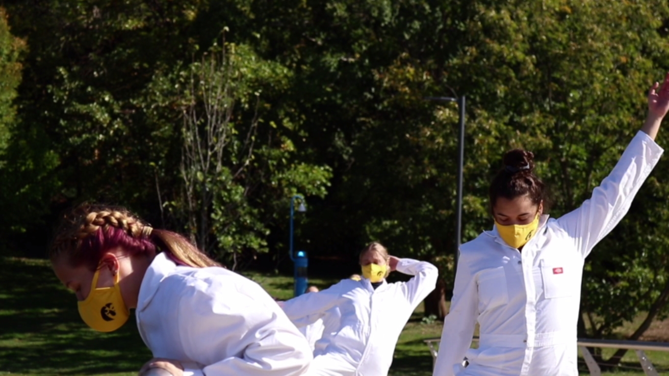 Three First-Year Seminar dancers in white with gold Hawkeye masks