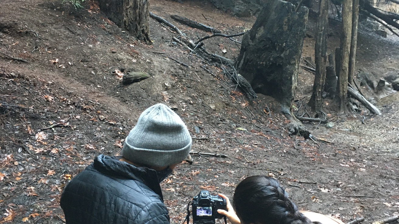 Two people reviewing camera shot in a wooded area