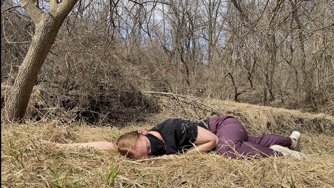 Dancer performing on the ground in a wooded area