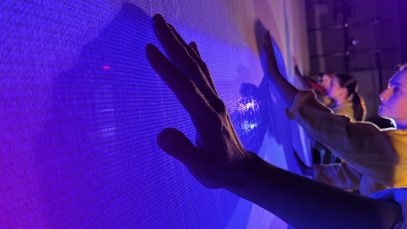 Dancers hands touching the video screen backdrop.